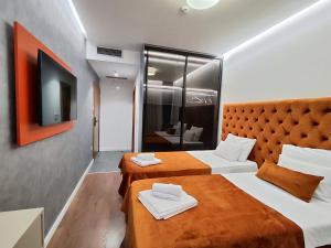 a hotel room with two beds and a television at Lolo Luxury rooms & suites in Budva