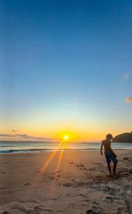 um homem parado na praia ao pôr do sol em Quarto Praia Santiago São Sebastiao 03 em São Sebastião