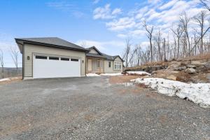 a house with a large white garage on a driveway at Muskoka Retreat Stunning Hilltop Views in Huntsville
