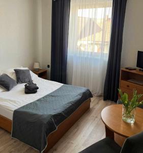 1 dormitorio con cama, mesa y ventana en KAMIENICA Pokoje & Restauracja, en Opalenica