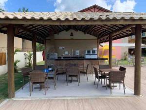 a patio with a table and chairs and a kitchen at 4 Suítes Pé na Areia Itacimirim in Camacari