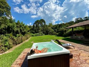 a woman laying in a hot tub in a backyard at Pousada Chalés Jardim das Bromélias - Visconde de Mauá in Visconde De Maua