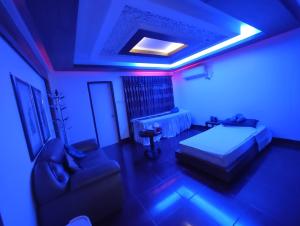 a bedroom with a bed and a couch and a blue light at Spas Personal Care in Dhaka