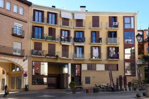 un edificio amarillo con balcones, mesas y sillas en Albada Huesca en Huesca