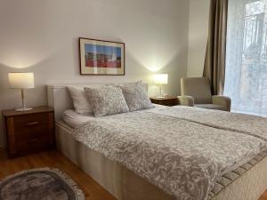 a bedroom with a bed and a chair and a window at Apartmani Maximus in Subotica