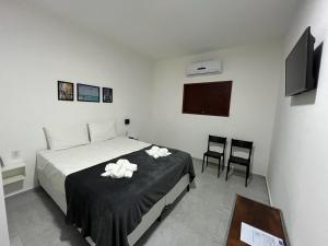 a bedroom with a bed and two chairs and a television at Marbello Pousada Gostoso in São Miguel do Gostoso