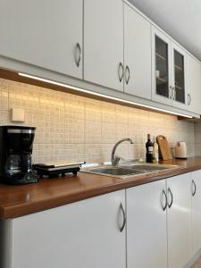 a kitchen with white cabinets and a sink at Corfu Lakeside Cottage in Kanoni