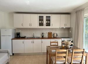 a kitchen with white cabinets and a table with chairs at Corfu Lakeside Cottage in Kanoni