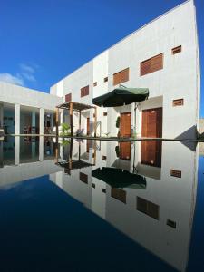 a building with a swimming pool with an umbrella at Marbello Pousada Gostoso in São Miguel do Gostoso