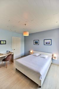 a bedroom with a large white bed and a desk at Laouen Blavezh'ti in Saint-Barthélemy