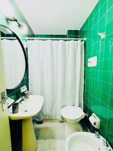 a green tiled bathroom with a sink and a toilet at Monoambiente/Studio Avenida Gaona Ramos Mejía in Ramos Mejía