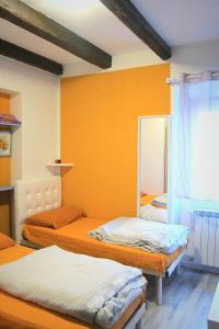 drie bedden in een kamer met oranje muren bij Camere Stone House in Trieste