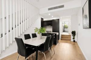 a dining room with a table and black chairs at Stylish New 3 BDRM house - Alexandria in Sydney