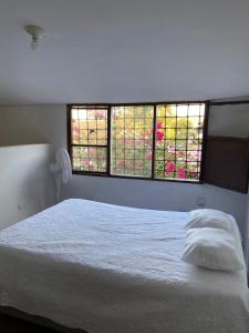 een wit bed in een slaapkamer met 2 ramen bij VEGAN ROOM in Barranquilla