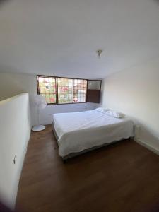 een witte slaapkamer met een bed en 2 ramen bij VEGAN ROOM in Barranquilla