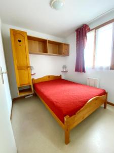 1 dormitorio con cama de madera y colcha roja en Appartement Ski Pied de Pistes - Valfréjus, en Modane