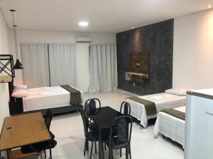 Lençóis Prime Apartments في لينكويس: غرفة بسريرين وطاولة وكراسي