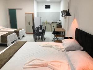 Lençóis Prime Apartments في لينكويس: غرفة نوم بسريرين ومطبخ مع طاولة