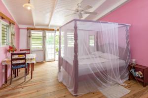 a bedroom with a bed with a mosquito net at Cabier Ocean Lodge in Crochu