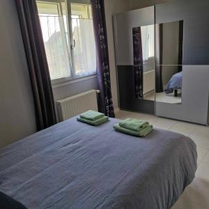 a bedroom with a bed with two green towels on it at Maison de vacances in Appenwihr