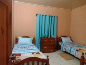 two beds in a room with blue curtains at Tessa's Inn in Arima