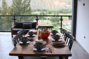 una mesa de madera con tazas y un tazón de comida. en Terraza house, en Huánuco