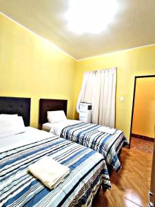 2 camas en una habitación con paredes amarillas en La Ruta, en Paracas