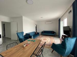 uma sala de estar com uma mesa de madeira e cadeiras azuis em Mavi Boncuk em Muğla