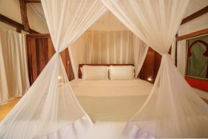 1 dormitorio con 1 cama con cortinas blancas en Pousada El Gordo, en Trancoso