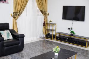 Sala de estar con silla negra y TV en Stunning Executive 2 Bedroom Apartment with KING SIZE BED en Kumasi