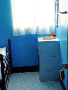 Baño azul con lavabo y ventana en Hostal Siero, en Moyogalpa