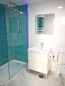 Un baño con lavabo y ducha de cristal. en OFIC/ESTUDIO CONIL S.A., en Conil de la Frontera