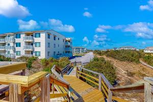 a wooden staircase leading to a beach with a building at Ocean Breeze 106B in Emerald Isle