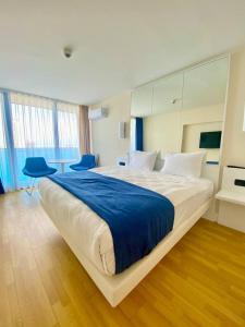 a large white bed in a room with blue chairs at Orbi City Sea View in Batumi