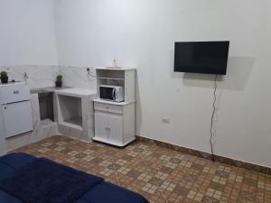 a kitchen with a microwave and a tv on a wall at Fashion Home in Guarambaré