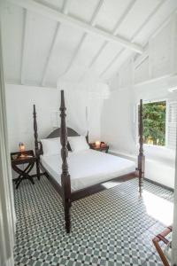 - une chambre blanche avec un lit et une fenêtre dans l'établissement La Petite Charmeuse, à Fort-de-France