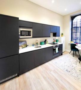 een keuken met zwarte kasten en een aanrecht bij Lovely and Modern Apartment in Leeds City Centre in Leeds