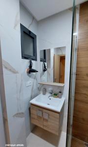a bathroom with a sink and a tv on the wall at اقامة الاحلام in Nador +27 photos