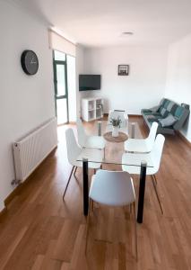 ein Wohnzimmer mit weißen Stühlen, einem Tisch und einer Couch in der Unterkunft PortoHome I in Portomarin