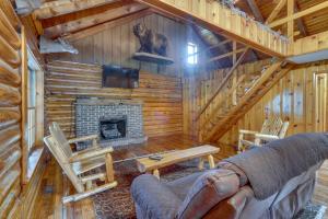 a living room with a fireplace in a log cabin at Rustic Wellston Cabin with Pond and ATV Trail Access! in Hamden