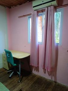 um quarto com uma secretária e uma janela com cortinas cor-de-rosa em Casa Mágica a orillas del Rio em Puerto Iguazú