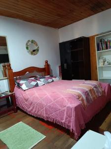 um quarto com uma cama com uma colcha rosa em Casa Mágica a orillas del Rio em Puerto Iguazú