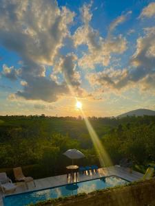 una piscina con el sol en el cielo en Recanto dos Passáros Penedo RJ, en Penedo