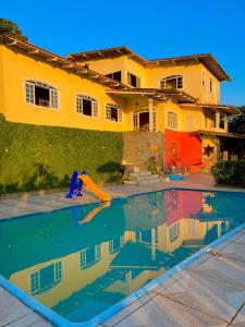 a man is swimming in a pool in front of a house at Recanto dos Passáros Penedo RJ in Penedo