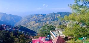 Blick auf eine Bergkette mit Bäumen und Gebäuden in der Unterkunft Boho Stays near mall in Shimla