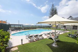 a swimming pool with lounge chairs and an umbrella at The Breakers in Gold Coast