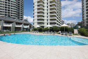a swimming pool with chairs and umbrellas in front of buildings at The Breakers in Gold Coast