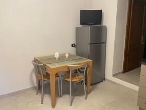 a table with chairs and a refrigerator in a room at Casa Vacanze Le Case in San Gimignano