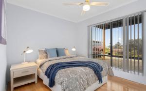 a white bedroom with a bed and a window at Hazel Beach House - Ocean Views & Coastal Charm in Goolwa South