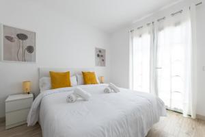 een witte slaapkamer met een groot wit bed met gele kussens bij Casa Moure in Costa Teguise